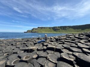 NAFAn, Mary Swanson, sitting with legs outstretched on the rock that makes up Giant's Causeway