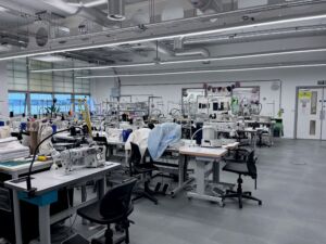 A classroom at Northumbria University with tables with sewing machines, measuring tape, mannequins, and other materials for fashion design. 