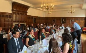 NAFAns participants attend a formal dinner at St. Catharine’s College, Cambridge, seated at a long candlelit table in a wood-paneled dining hall.