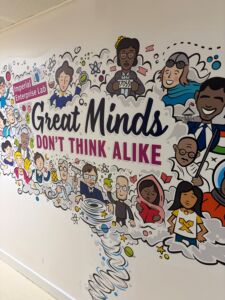 A cartoon idea cloud with men and women scientists and thinkers from a variety of backgrounds are shown with their inventions or texts and centralized text reads “Great Minds Don’t Think Alike”
